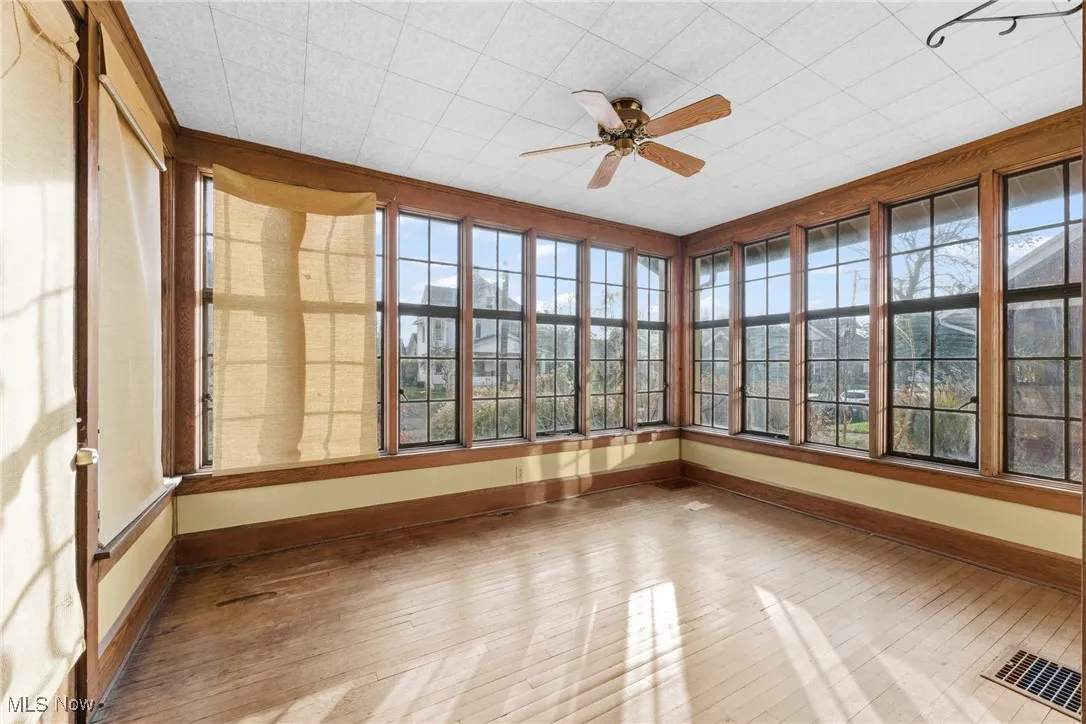 Unfurnished sunroom with baseboards and wood-type flooring