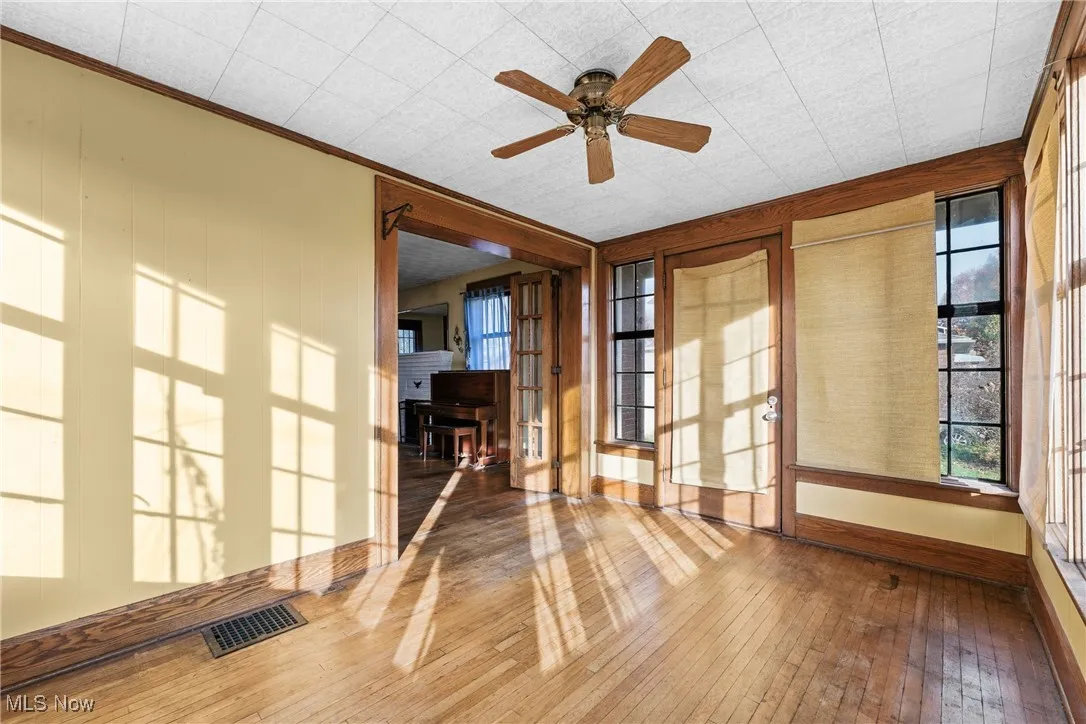 Unfurnished room with hardwood / wood-style floors, ceiling fan, plenty of natural light, and crown molding