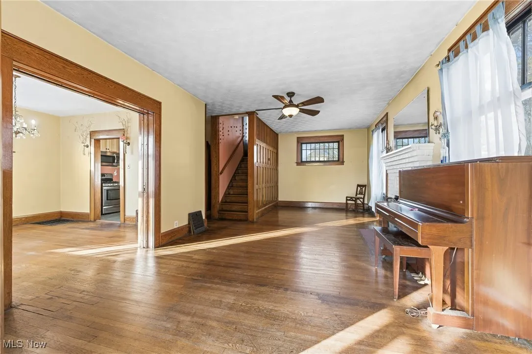 Living room featuring wood-type flooring, ceiling fan, stairway, and a chandelier