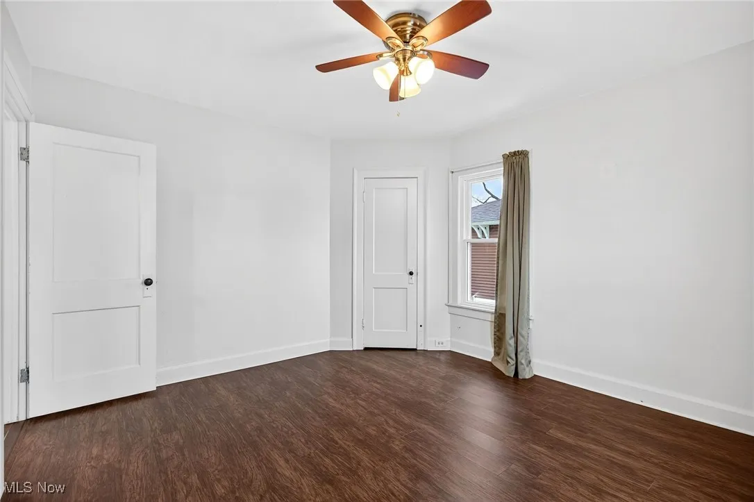 Unfurnished bedroom featuring dark wood-style flooring and ceiling fan