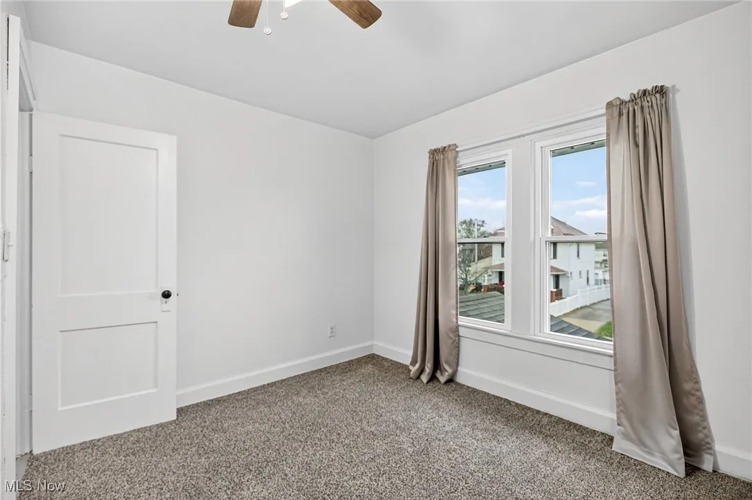 Carpeted spare room with baseboards and a ceiling fan