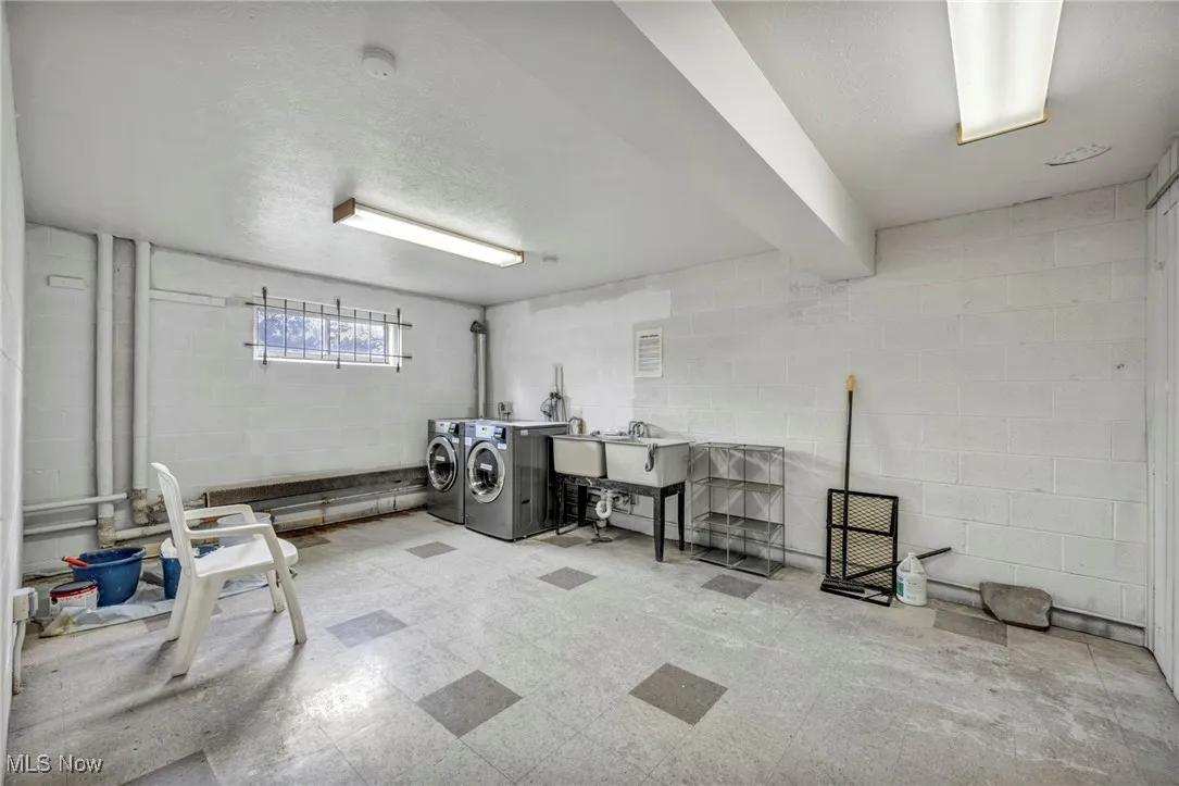 Basement featuring concrete block wall, tile patterned floors, washing machine and clothes dryer, and a textured ceiling