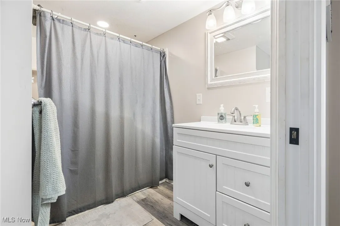 Full bath featuring a stall shower, vanity, and light wood-style flooring