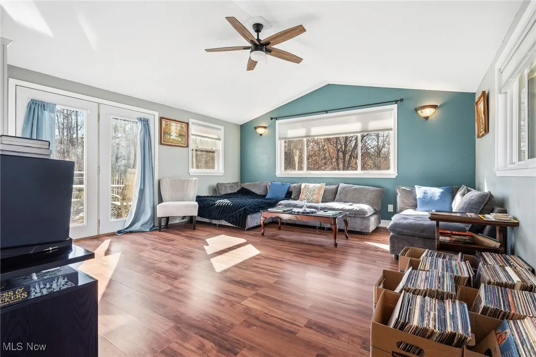 Living room featuring wood finished floors, vaulted ceiling, healthy amount of natural light, and ceiling fan