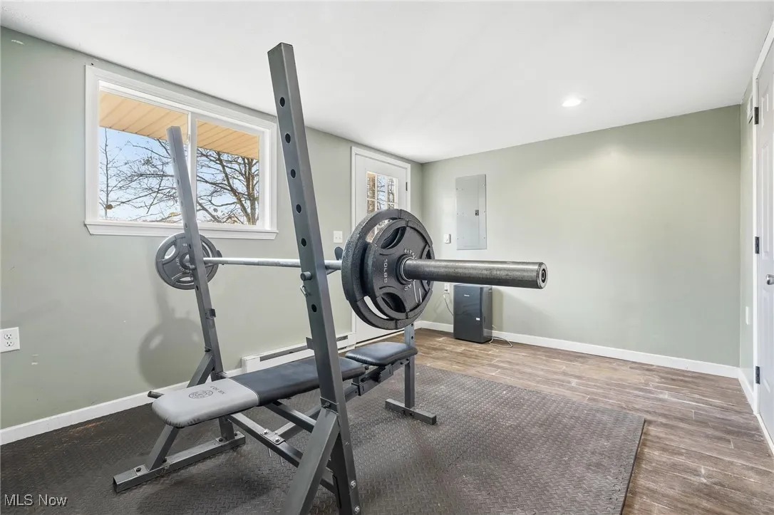 Workout room with electric panel, recessed lighting, wood finished floors, and a baseboard radiator