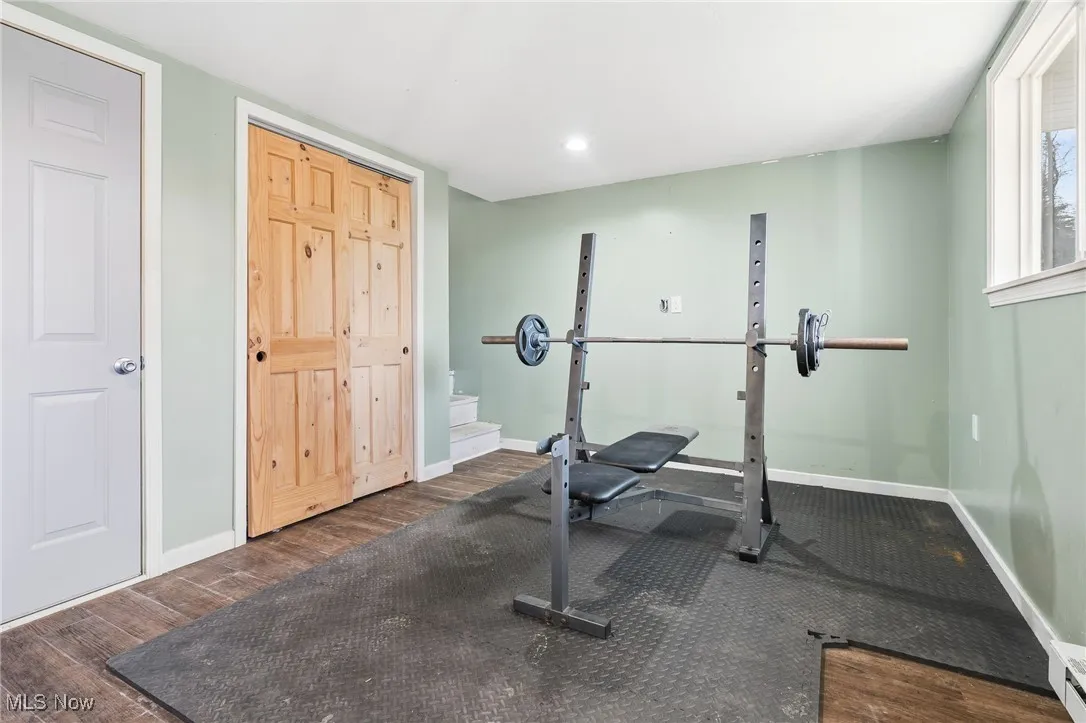 Workout area with wood finished floors, a baseboard radiator, and recessed lighting