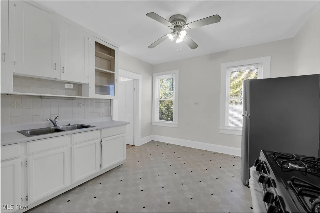 Kitchen featuring light countertops, white cabinets, decorative backsplash, and open shelves