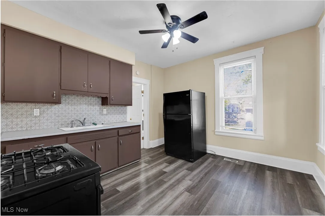 Kitchen featuring black appliances, light countertops, dark wood finished floors, tasteful backsplash, and dark brown cabinets