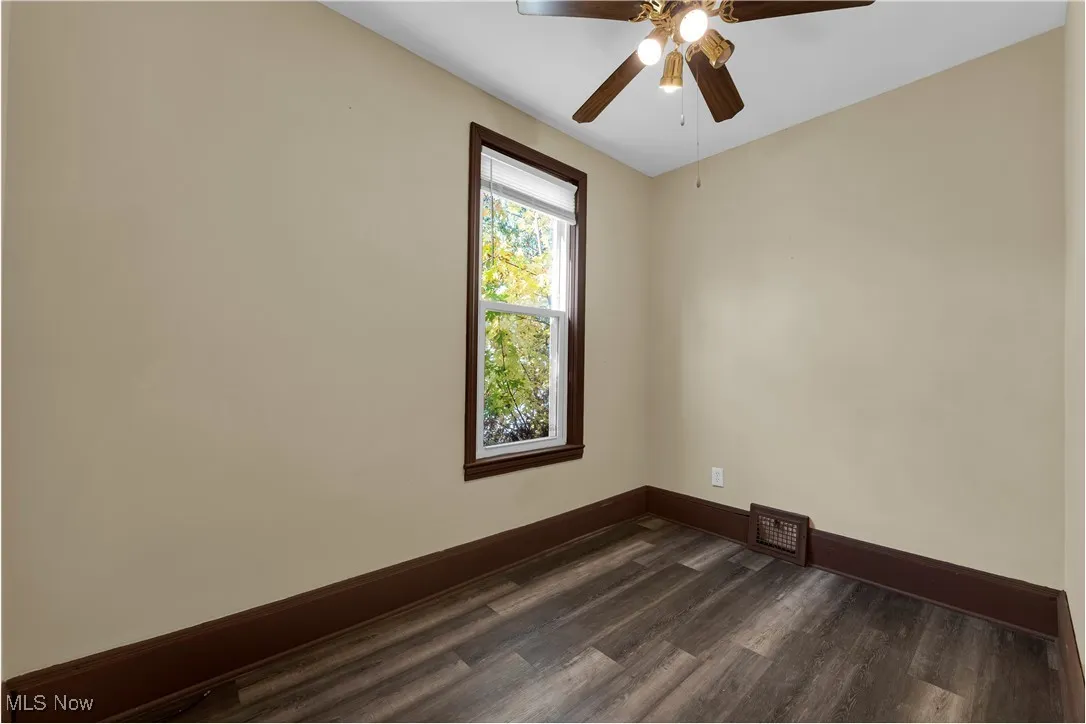 Spare room with dark wood-type flooring and a ceiling fan
