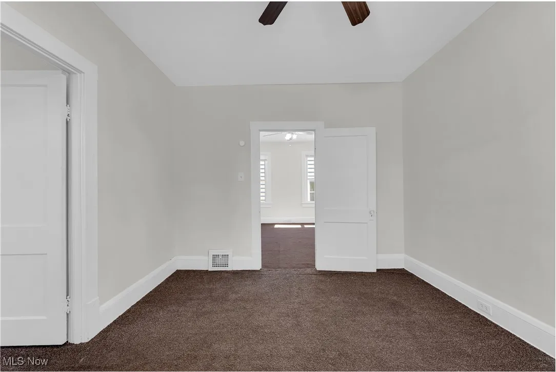 Spare room with dark carpet and a ceiling fan