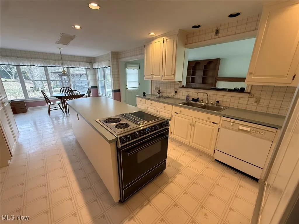 Kitchen with light flooring, black range with electric stovetop, a center island, healthy amount of natural light, and recessed lighting