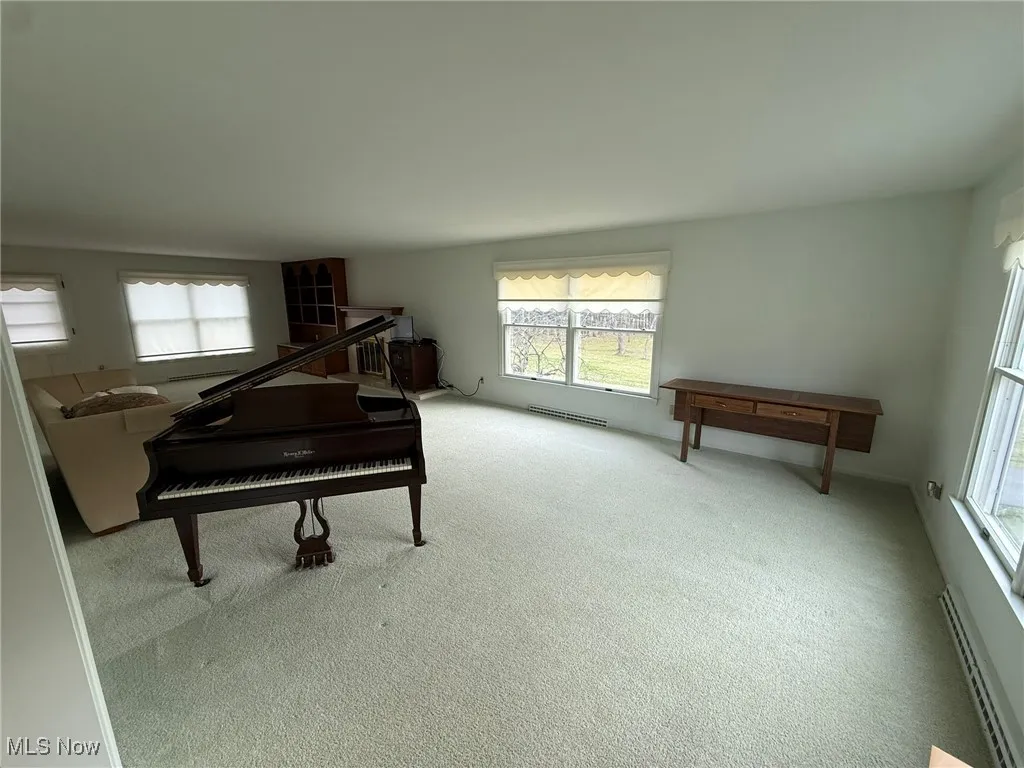 Living area with a baseboard heating unit, healthy amount of natural light, and carpet