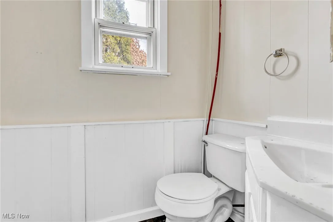 Half bath with wainscoting, vanity, and a decorative wall