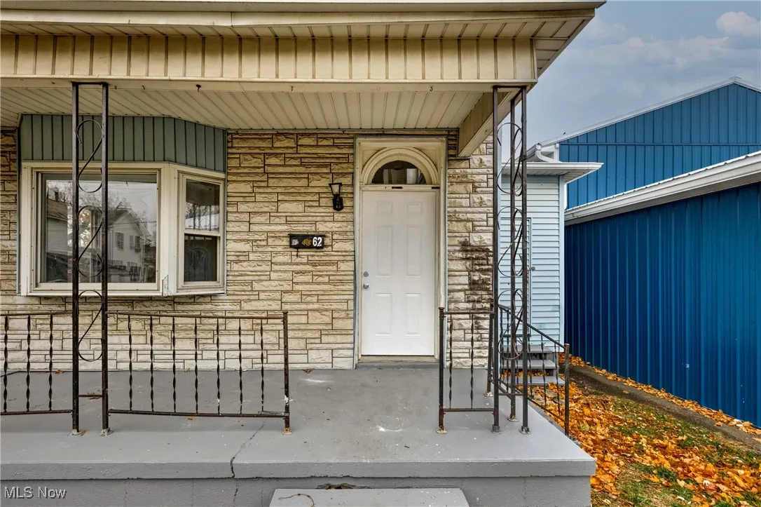 Doorway to property with stone siding and covered porch