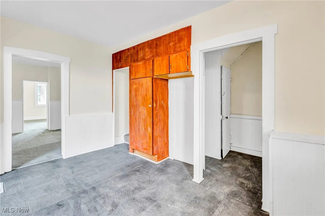 Unfurnished bedroom with wainscoting and a closet