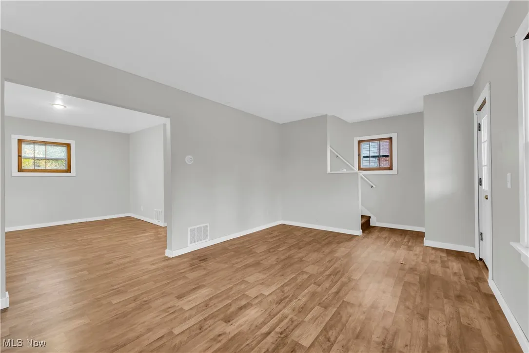 Empty room with light wood-type flooring, healthy amount of natural light, and stairs