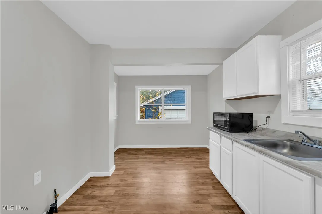 Kitchen featuring light countertops, plenty of natural light, white cabinets, and light wood-type flooring
