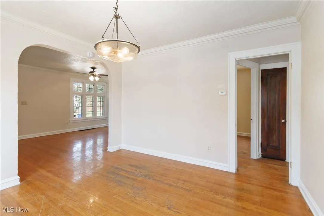 1st Floor room featuring crown molding, arched walkways, light wood-style flooring, and a ceiling fan