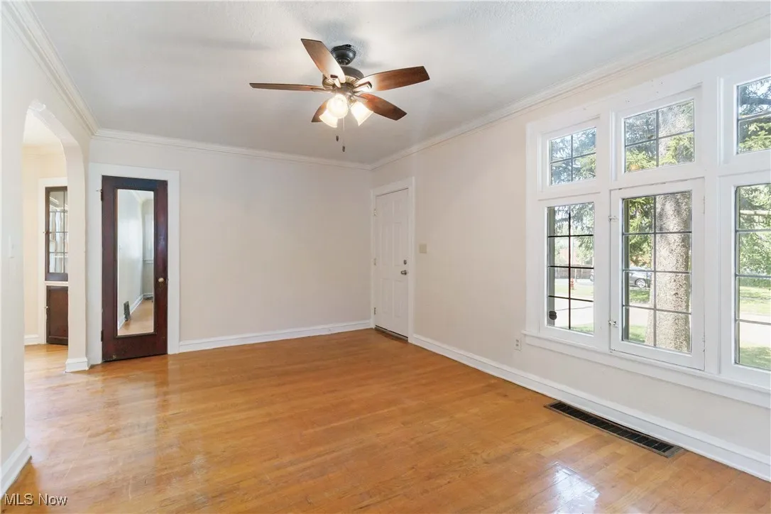 1st Floor Living room featuring light wood-style flooring, crown molding, arched walkways, and a ceiling fan