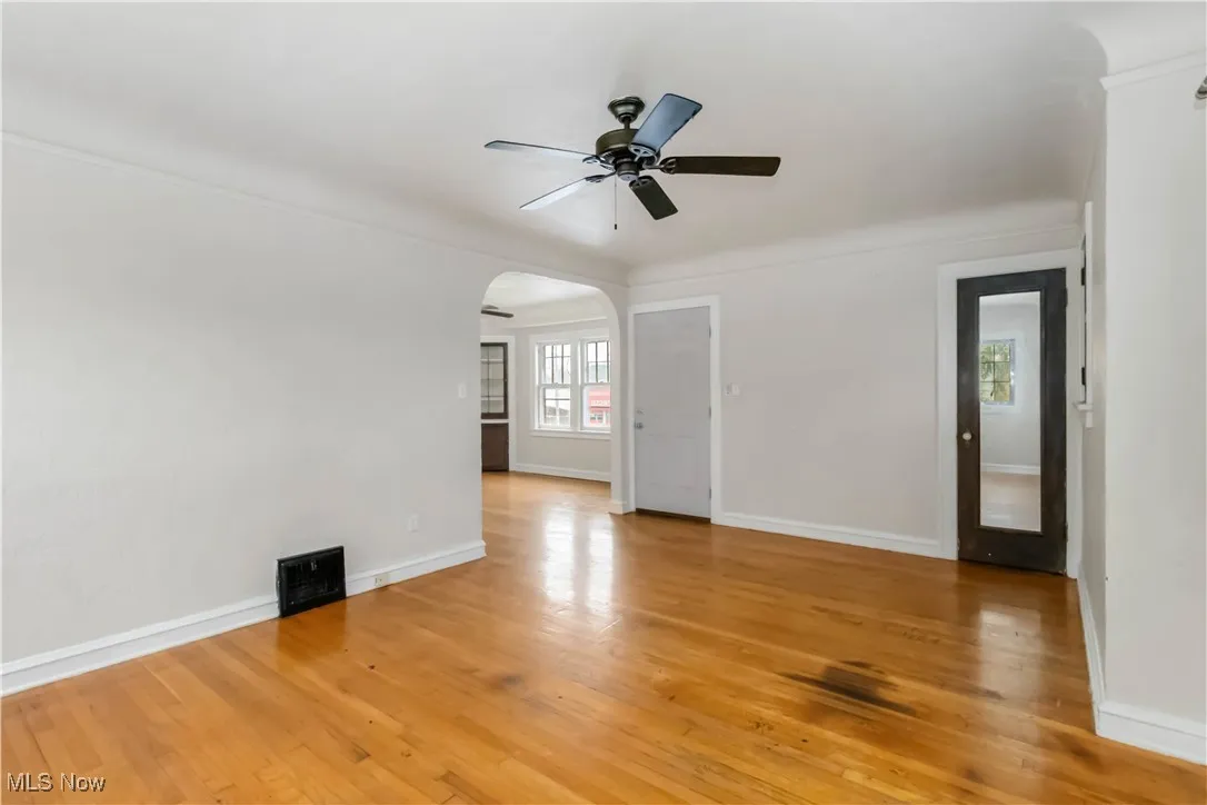 2nd floor living room featuring arched walkways, light wood-style flooring, ceiling fan, and crown molding