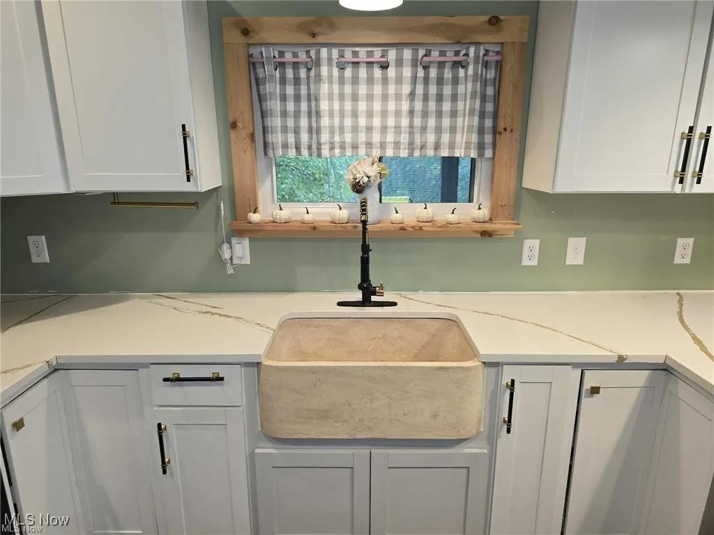 Kitchen view of white cabinetry and light stone counters