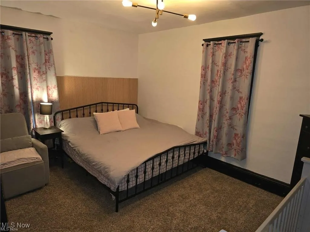 Bedroom featuring a wainscoted wall, wooden walls, and carpet