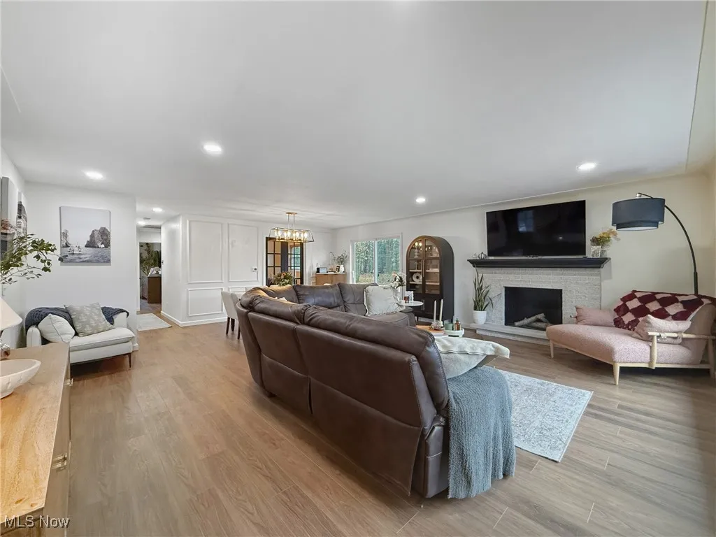 Living room featuring recessed lighting, light wood-type flooring, a fireplace with raised hearth, and a chandelier