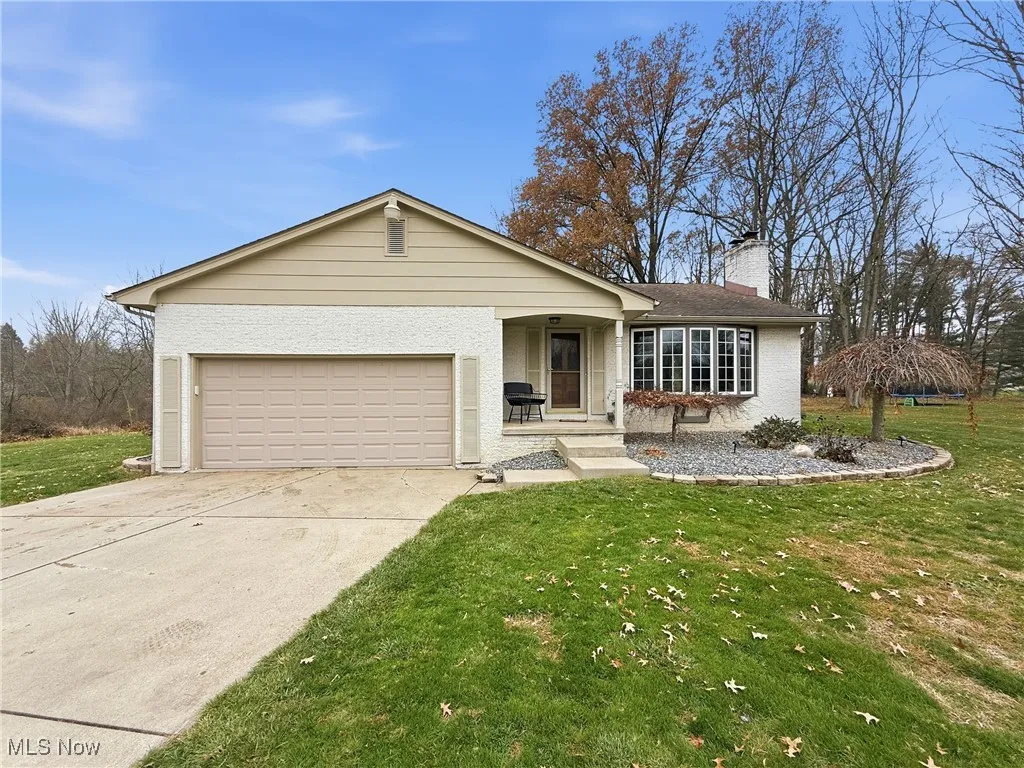Ranch-style home with a front lawn, driveway, a chimney, and brick siding