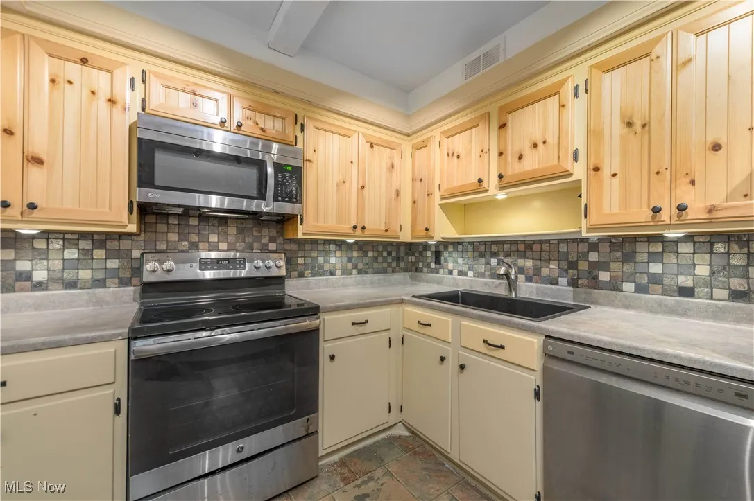 Kitchen with appliances with stainless steel finishes, backsplash, and light countertops