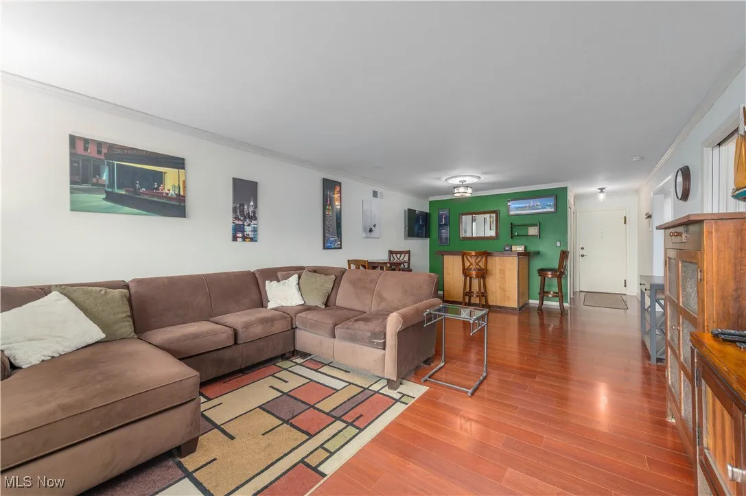 Living area with ornamental molding and wood finished floors