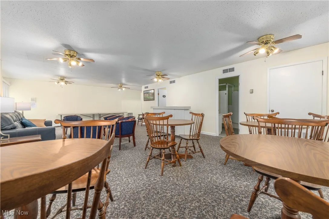 Party room with a textured ceiling, ceiling fan, and carpet