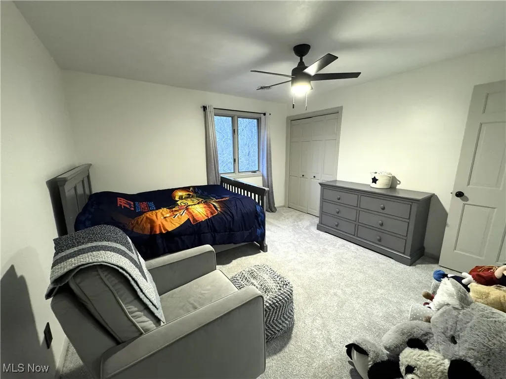 Carpeted bedroom featuring a closet and ceiling fan