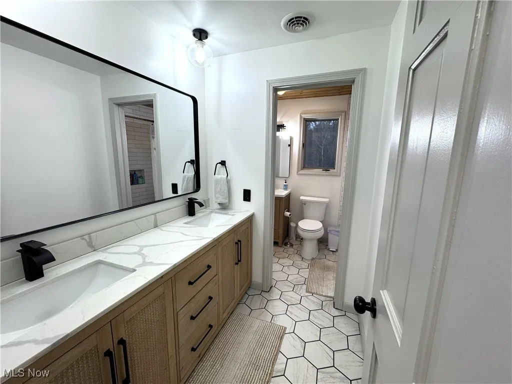 Full bath featuring double vanity and light tile patterned floors
