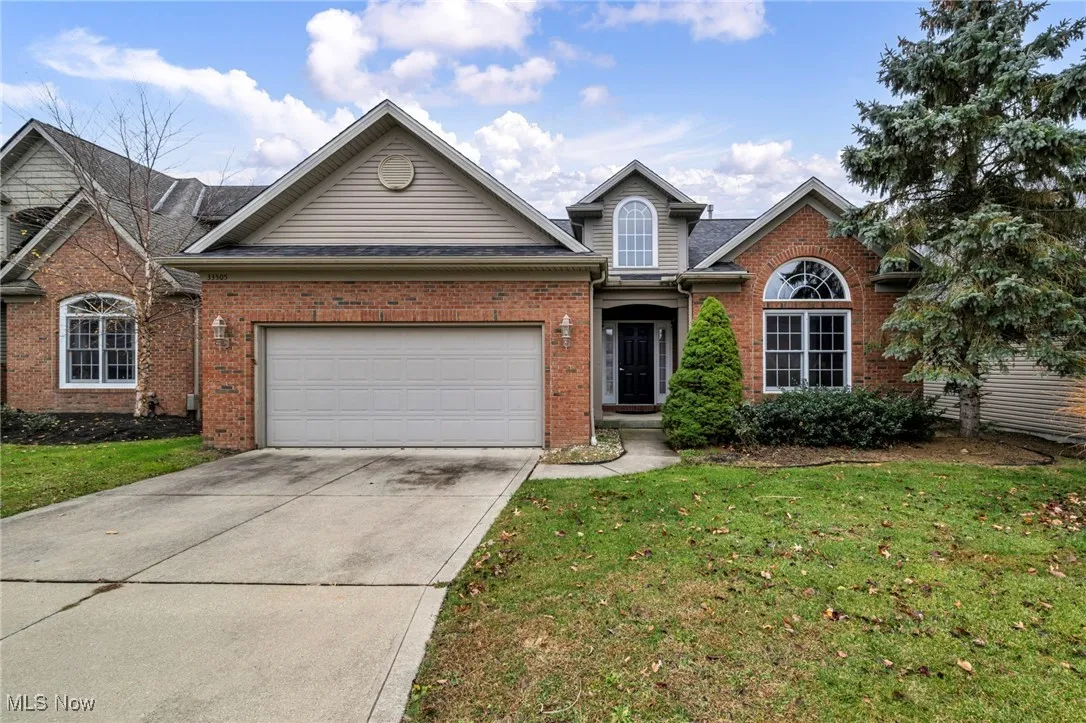 Traditional-style home with brick siding, concrete driveway, a front lawn, and a garage