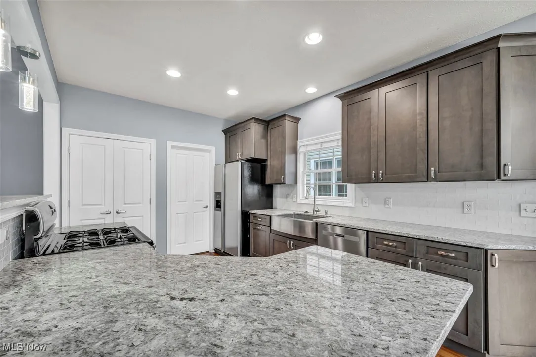 Kitchen featuring decorative backsplash, dark brown cabinetry, recessed lighting, light stone countertops, and a peninsula