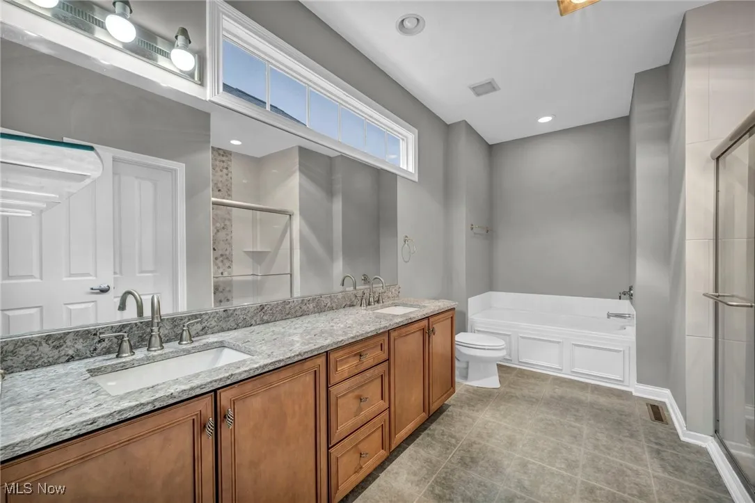 Bathroom with a garden tub, double vanity, a stall shower, light tile patterned floors, and recessed lighting