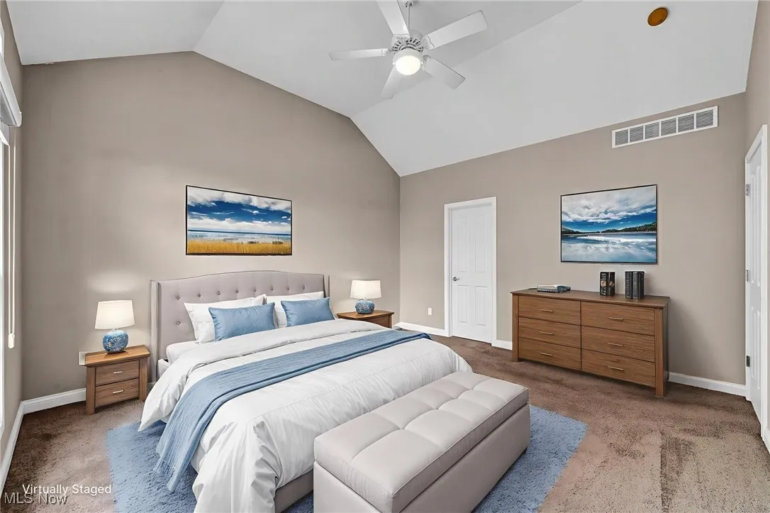 Carpeted bedroom featuring vaulted ceiling and ceiling fan