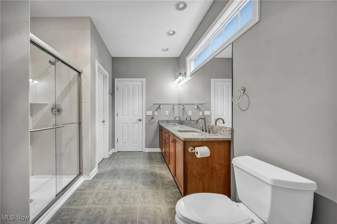 Full bath with double vanity, a stall shower, light tile patterned flooring, and recessed lighting