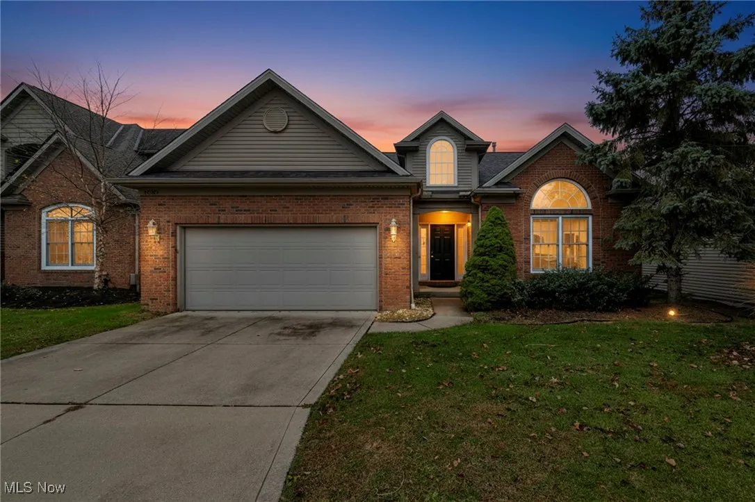 View of front of property with concrete driveway, brick siding, a garage, and a front lawn