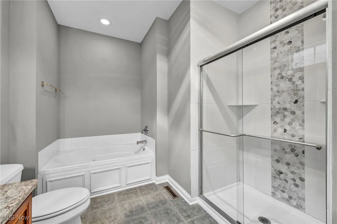 Bathroom with a bath, a stall shower, vanity, tile patterned floors, and recessed lighting