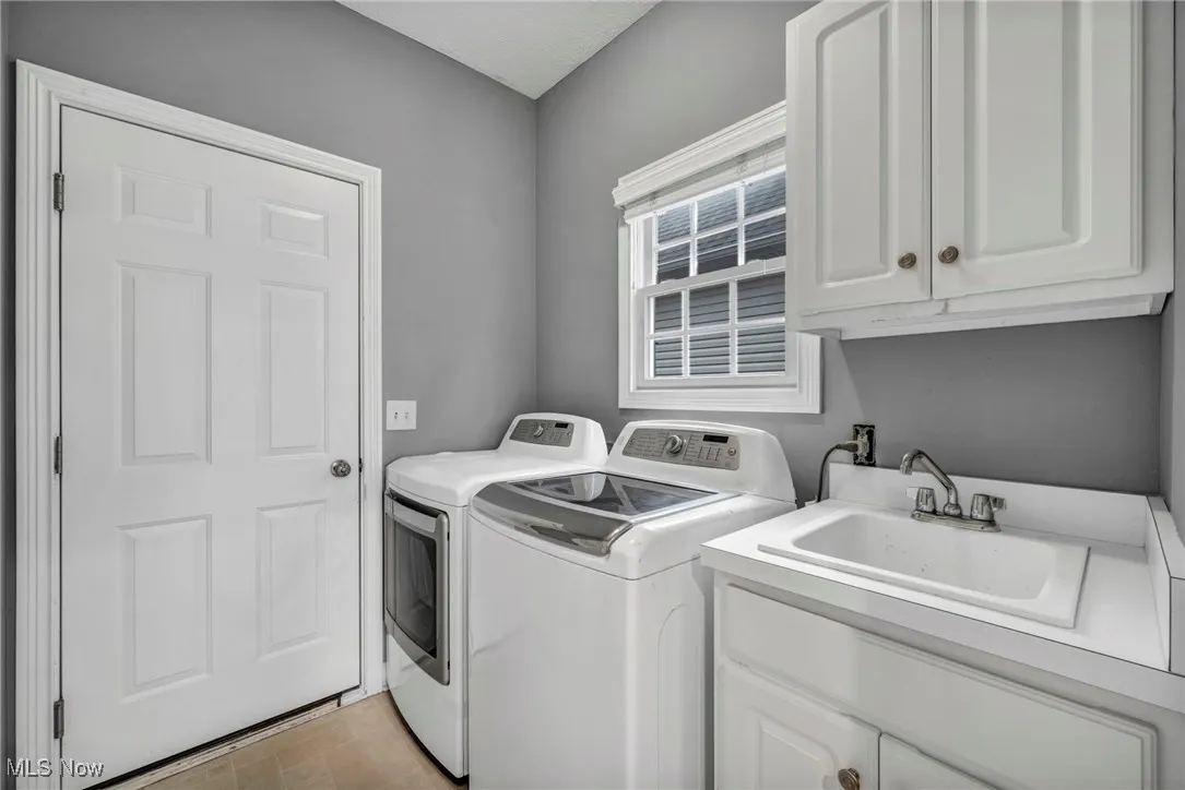 Washroom with cabinet space, washing machine and dryer, and light tile patterned floors