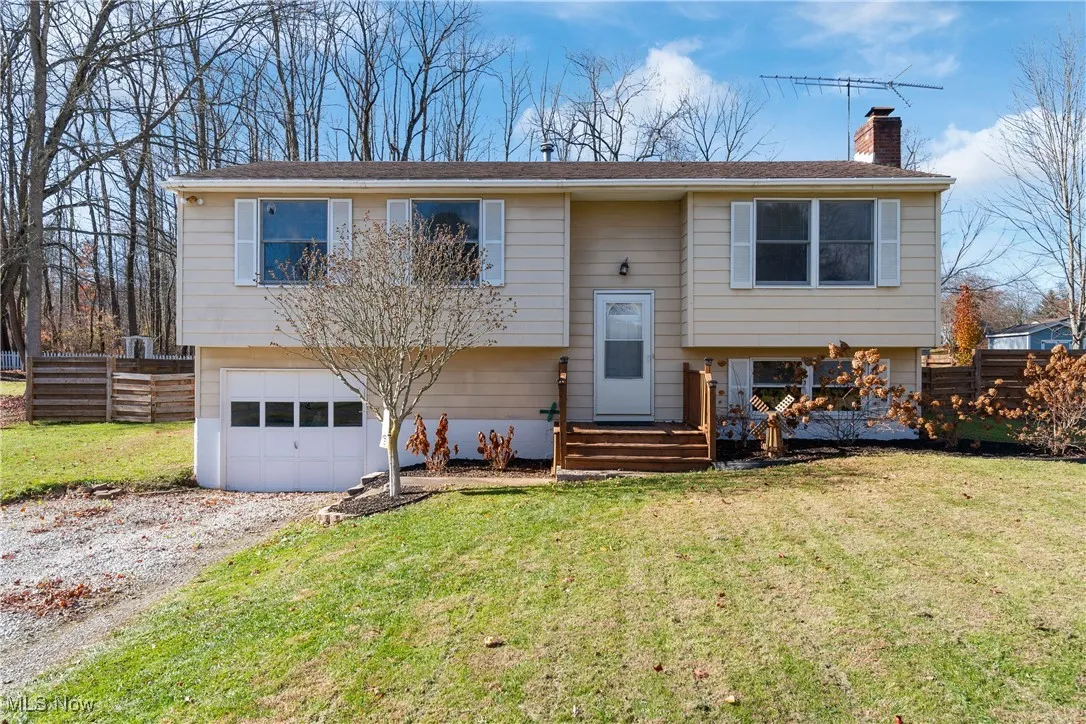 Bi-level home with a chimney, gravel driveway, and attached garage