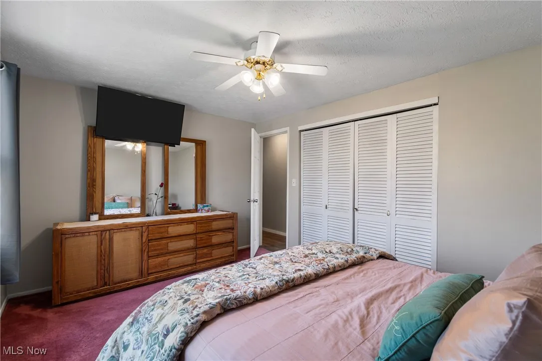 Bedroom with carpet flooring, ceiling fan, a textured ceiling, and a closet