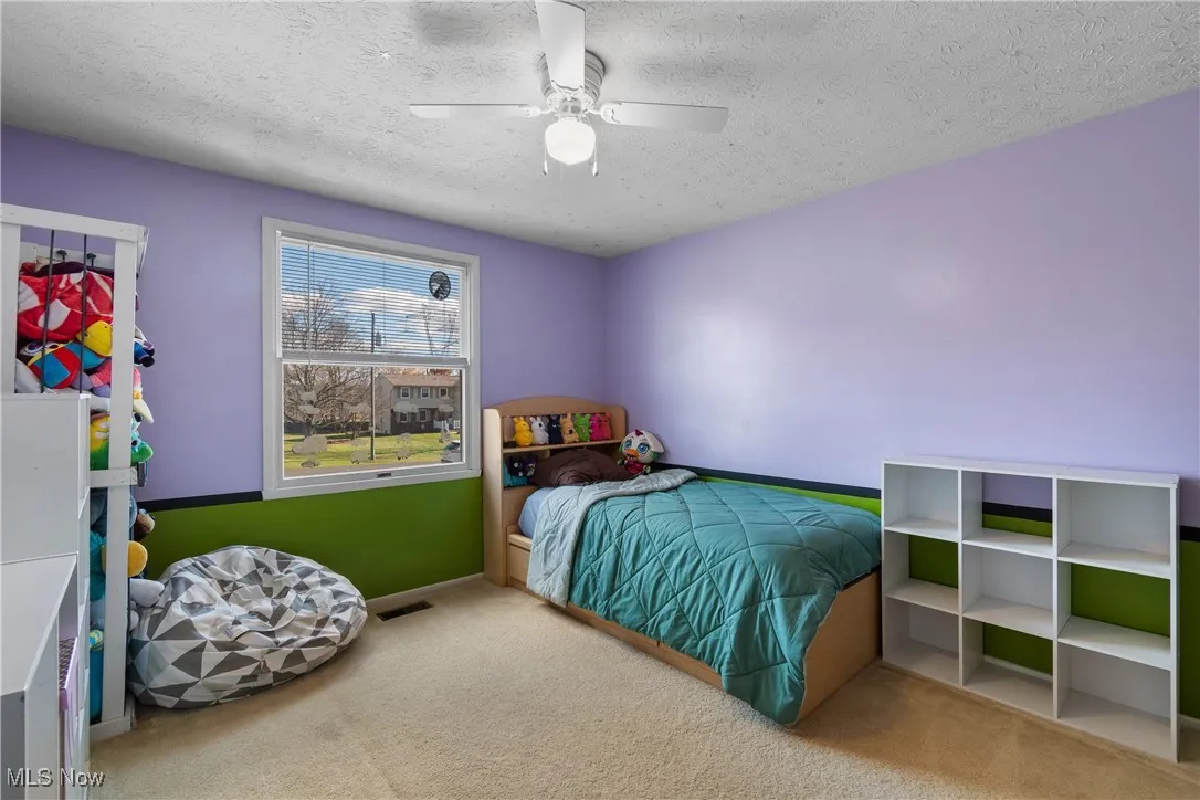 Bedroom with carpet flooring, a textured ceiling, ceiling fan and a window