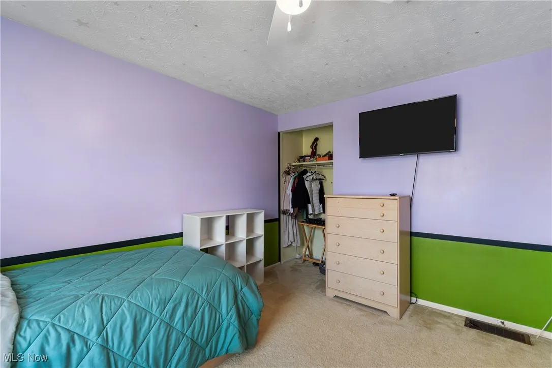 Carpeted bedroom featuring a closet, a textured ceiling, and a ceiling fan