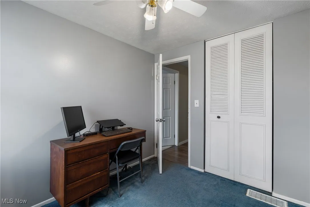 3rd Bedroom is currently being used as an office, dark carpet flooring, a textured ceiling, ceiling fan and a closet