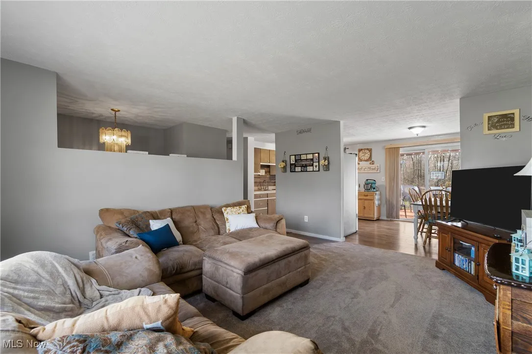 Living room view looking towards the kitchen, with carpet flooring and a textured ceiling