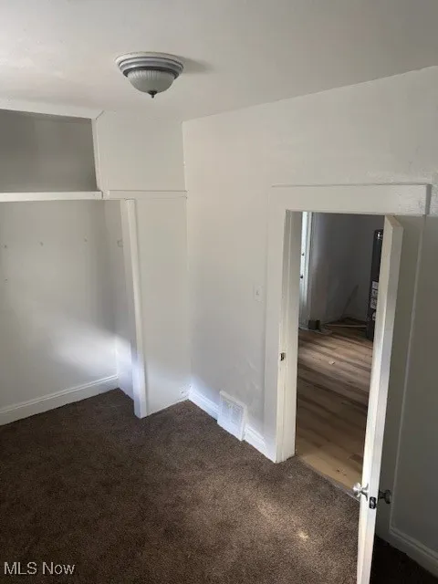 Unfurnished bedroom with dark colored carpet and a closet