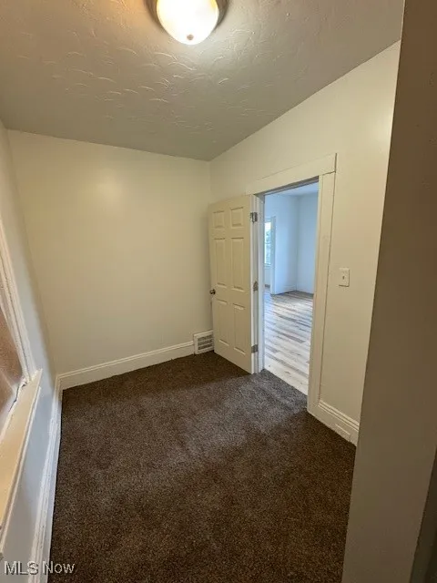 Bedroom featuring dark carpet and a textured ceiling