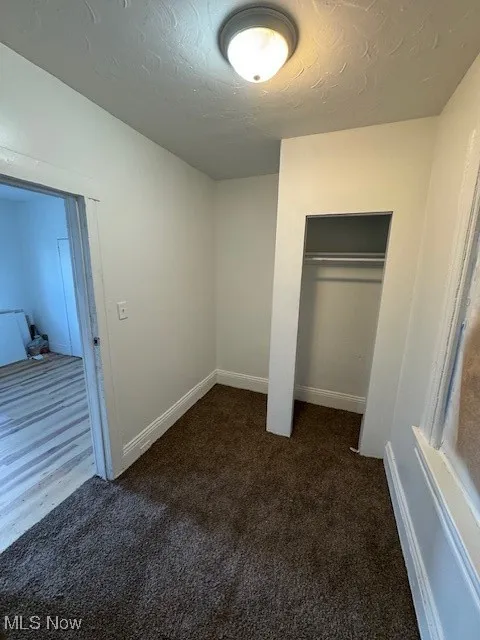bedroom with dark colored carpet, a closet, and a textured ceiling